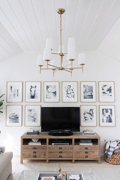 a living room with pictures on the wall and a television in the center, along with a coffee table