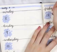 a woman is writing on a planner with her hand