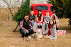 a group of people sitting next to each other in front of a red truck with santa hats on