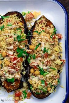 two stuffed eggplant halves covered in rice and veggies on a plate