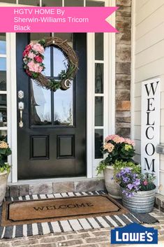 a welcome mat on the front door of a house with flowers in buckets next to it