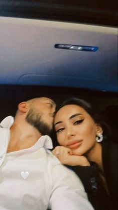 a man and woman laying in the back of a car