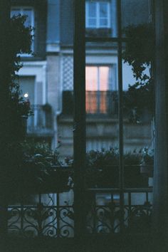 an open window with the words written in arabic on it at night, and some potted plants outside