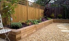 an outdoor garden area with wooden fence and plants in the center, surrounded by gravel