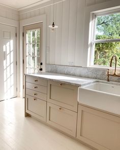 an empty kitchen with white cabinets and marble counter tops is seen in this image from the doorway