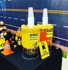 a table topped with yellow buckets filled with orange liquid and other items on top of it