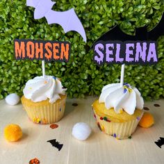 two cupcakes decorated with white frosting and sprinkles are sitting on a table