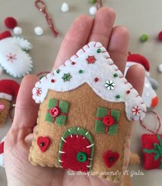 a hand holding a small felt house ornament