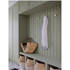 a bench with baskets on it next to a coat rack and shoes hanging up against the wall