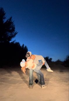 a man holding a child in the sand at night