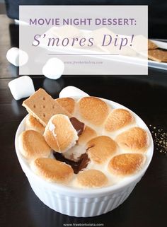 a dessert dish with marshmallows and graham crackers in the middle on a black table