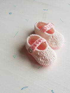 a pair of crocheted baby shoes sitting on top of a white tablecloth