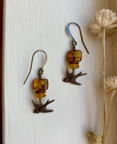 "murmuration ~ vintage-style antique brass bird earrings with earthy tortoiseshell amber, terracotta, wildflower yellow, and gleaming accents Details & measurements: ~ Sweet little antique brass, vintage style bird charms (17 x 7mm) are hanging from  gorgeous small rectangle amber Czech glass beads with an earthy Picasso finish, giving them a tortoiseshell look (12 x 8mm) ~ Accented by Czech glass rondelle spacer beads in matte terracotta (7mm), frosted wildflower yellow colored saucer beads (6mm), and tiny sparkling metallic Czech glass spacer beads ~ They hang from antique brass ear wires ~ Earrings hang approx. 1 3/4\" long ♡ Packaged safely & sustainably in a kraft box with cotton ribbon & dried organic florals. This makes for a beautiful gift, or something pretty for yourself! All pac Earth Tone Jewelry, Earthy Earrings, Boho Birds, Cottagecore Jewelry, Brass Bird, Cotton Ribbon, Store Jewelry, Earrings Antique, Bird Charm