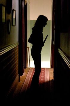 a woman is standing in the hallway with an umbrella over her head and holding a knife