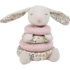 a stuffed bunny sitting on top of a stack of pillows in pink and white flowers