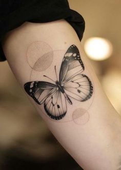 a black and white butterfly tattoo on the right arm, with circles around it's wings