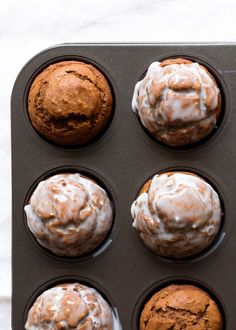 six muffins with icing in a baking pan