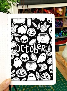 a person holding up an open book with halloween images on it and the words october written in black