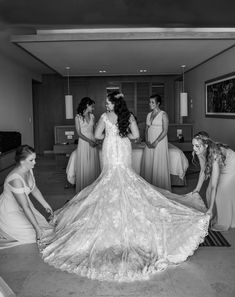 bridesmaids help the bride put on her wedding dress