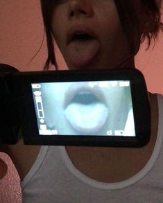 a woman holding up a cell phone to take a selfie with her mouth open