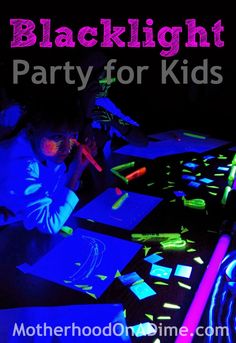 a young child is sitting at a table with neon lights on it and writing in the dark