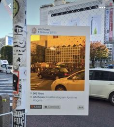 a poster on a pole in the middle of a street with cars parked along it