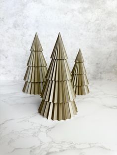 three wooden christmas trees sitting on top of a marble countertop next to each other