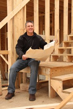 a man sitting on top of a wooden bench in front of a building under construction