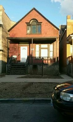 a car parked in front of a brick house with stairs leading up to the second story