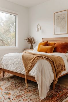 a bedroom with a bed, rugs and pictures on the wall above it in front of a window