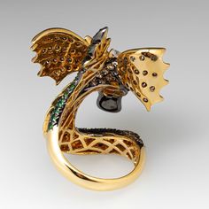 The Neda Behnam ring features a dragon design with the body, head and wings pave' set with a total of two hundred eleven (211) round brilliant cut champagne diamonds. The top of the head is pave' set with fifteen (15) white diamonds. The tail and eyes are pave' and bezel set with a total of forty-seven (47) round mixed cut tsavorite garnets. The ring measures 40.5mm at the top, rises 18.2mm above the finger, tapering to 3.7mm wide and 1.6mm thick at the base of the shank. The ring is currently a size 9.5 and we offer complimentary resizing to fit. Luxury Diamond Snake Ring, Luxury Snake Ring With Diamond Accents, Luxury Diamond Snake Ring With Pave Setting, Luxury Diamond Snake Ring With Single Cut Diamonds, Dragon Ring, Tsavorite Garnet, Dragon Design, Champagne Diamond, A Dragon