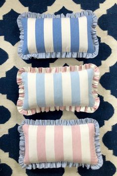 three blue and pink pillows sitting on top of a rug