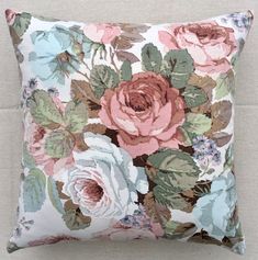 a pink and blue floral pillow sitting on top of a couch