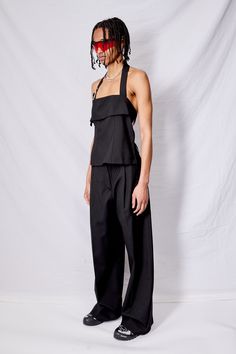 Black Suiting Belted Strap Halter Top from Assembly New York. Multi panel constructed crop-top with adjustable halter strap. Semi-open back with two snap-closing straps. Adjustable fit throughout for convertible styling. Silver metal hardware. Durable, tear-resistant suiting fabric. Sizing up recommended. - 100% Tropical wool - Dry clean only - Made in USA - Da'ani is 5'9" and size 2 and shown in size S with Assembly Green Houndstooth Suiting Homme Pant﻿, Assembly Black Suiting Homme Pant, and Salewa footwear. Jewelry by Martine Ali. Suiting Fabric, Halter Strap, Black Suits, Metal Hardware, Halter Top, Metallic Silver, Made In Usa, Size 2, Crop Top