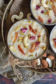 three bowls of oatmeal with nuts and dried fruit on the side, sitting on a table