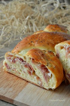 a ham and cheese roll cut in half on a cutting board next to some straw