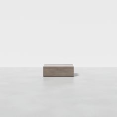 a square object sitting on top of a white floor in front of a gray wall