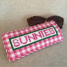 a pair of sunglasses sitting on top of a pink and white checkered case with the word sunnies printed on it