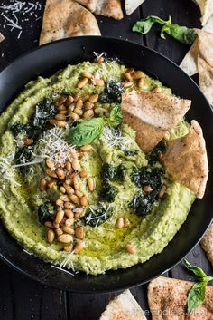 guacamole with spinach, pine nuts and parmesan cheese in a black bowl