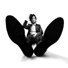 a black and white photo of a person sitting on the ground with their feet up