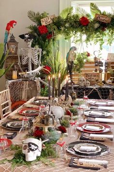 a table set for halloween dinner with skeleton decorations and greenery on the table top