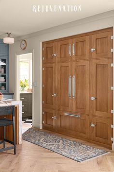 a large wooden cabinet in a kitchen next to a table and chair with a rug on the floor