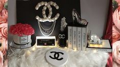 a chanel display with pink roses, pearls and other accessories on it's table