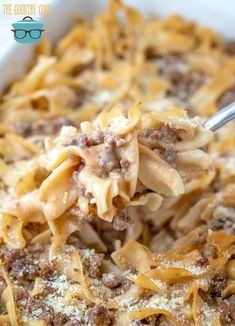 a spoon full of pasta with ground beef and parmesan cheese in a casserole dish