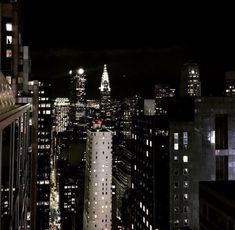 the city skyline is lit up at night, with skyscrapers in the foreground