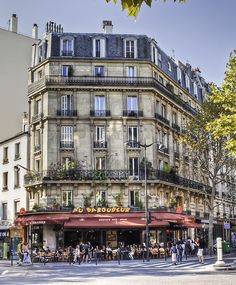 people are walking around in front of a building with many windows and balconies