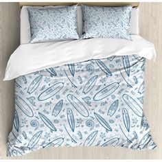 a bed with blue and white surfboards printed on the comforter, along with two pillows