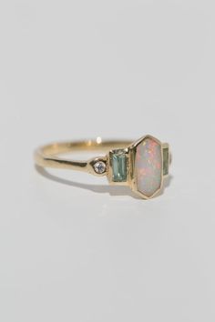 Art deco inspired ring with Australian opal, with either aquamarine and diamonds, or rubies. The opal is inlaid into the elongated hexagon, measuring 9.5mm x 5mm. Accent aquamarine and diamonds are approximately .30 total carat worth. Millimeter measurement from end to end is 15mm. Your choice of gold color and karat. The band is 1.75mm thick. Please leave a note at checkout with your preferred size. All gems and rocks are nuanced in color, please know that your ring will be very similar to the Opal Accent Engagement Ring, Opal Diamond Ring Engagement, Inlaid Opal Ring, Gemstone Engagement Rings Opal, Hexagon Opal Ring, Aquamarine Rings Vintage, Hazel Engagement Ring, Diamond Opal Ring, Opal Engagement Ring White Gold