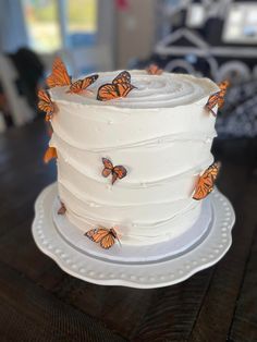 a white cake with orange butterflies on it