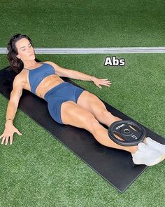 a woman laying on top of a black mat with the words abs above her head